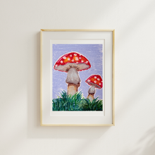 Load image into Gallery viewer, Framed artwork of two red mushrooms with white spots on a grassy patch against a light purple background.