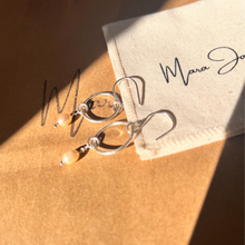 Load image into Gallery viewer, A pair of sterling silver earrings with freshwater pearls, displayed on a card with a signature.
