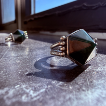 Load image into Gallery viewer, Two rings with green gemstones on a textured surface
