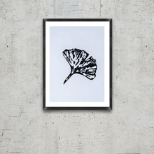 Load image into Gallery viewer, Framed artwork of a black leaf on a white background, hanging on a textured gray wall.
